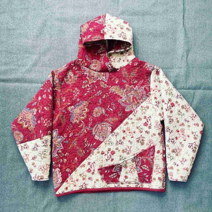 a red and white jacket sitting on top of a bed.