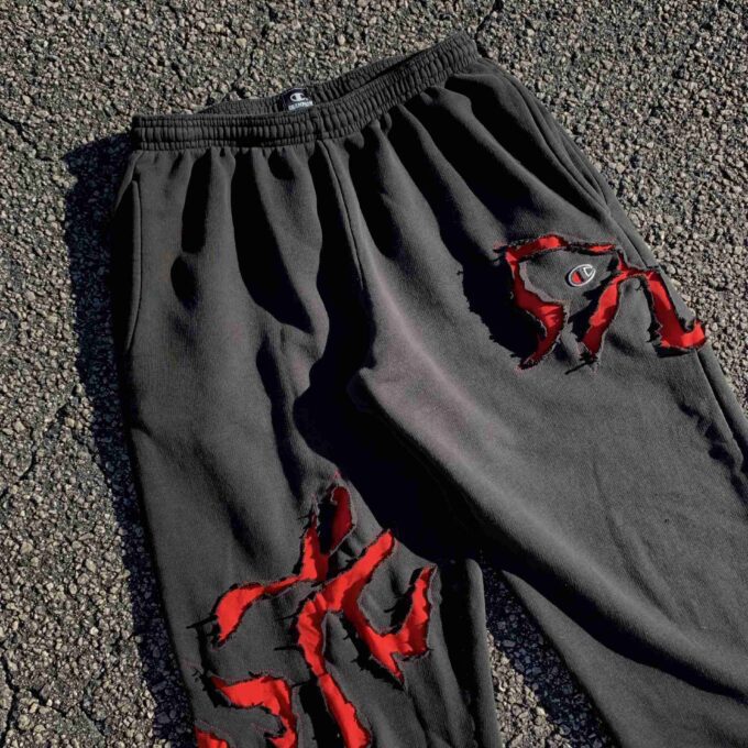 a pair of black sweatpants with red paint on them.