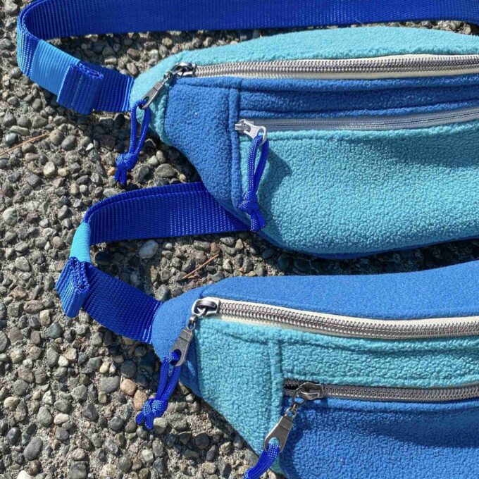 a pair of blue fanny bags sitting on top of a gravel road.