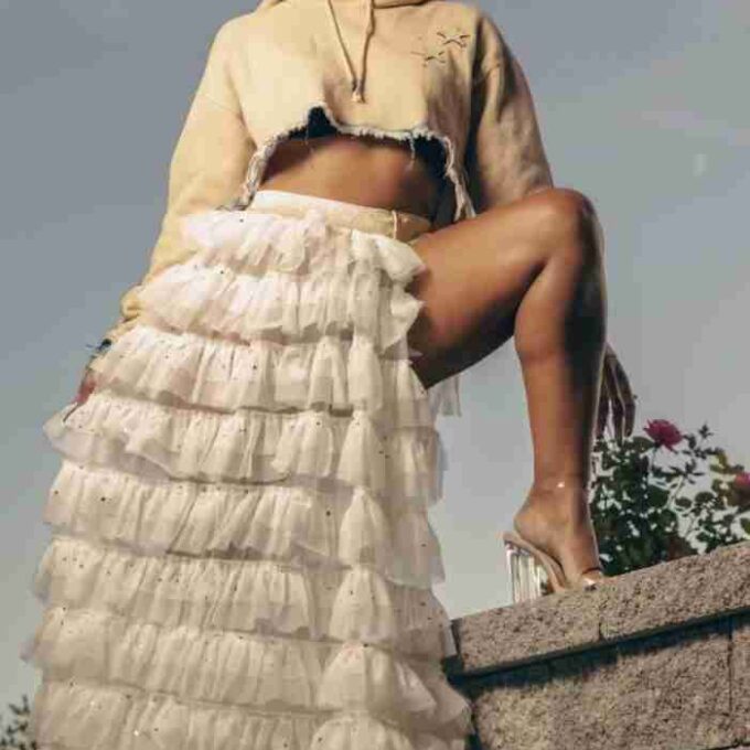 a woman in a skirt sitting on top of a stone wall.