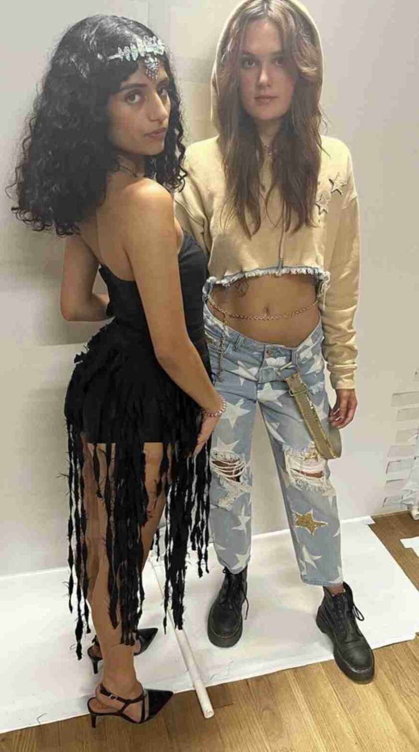 two women standing next to each other in front of a mirror.