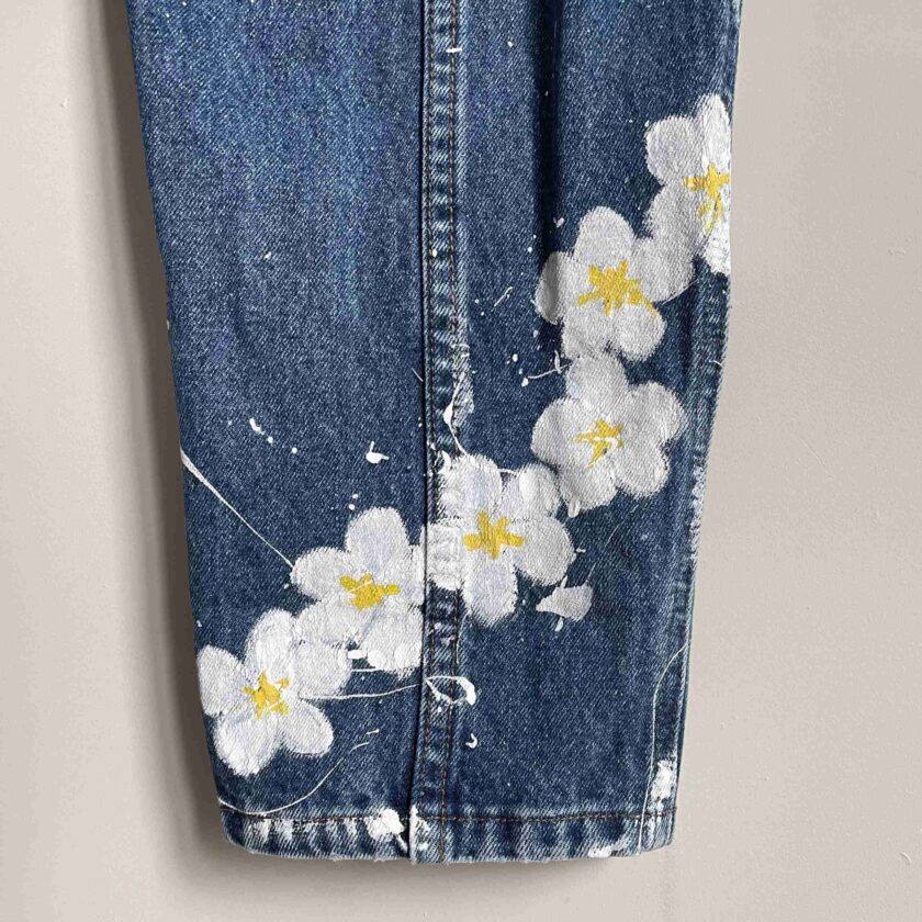 a pair of jeans with flowers painted on them.