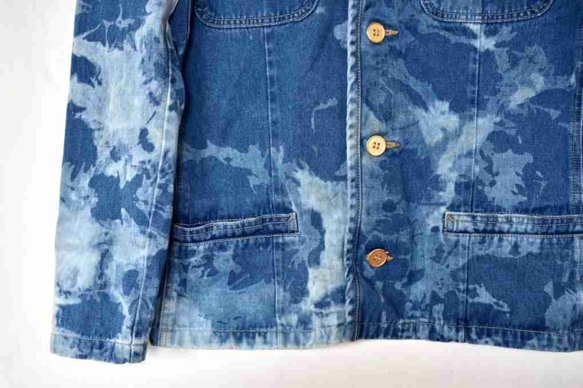 a blue jean jacket hanging on a white wall.