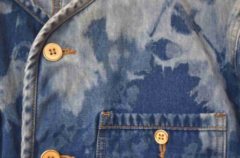 a tie dye denim jacket with buttons on the back.
