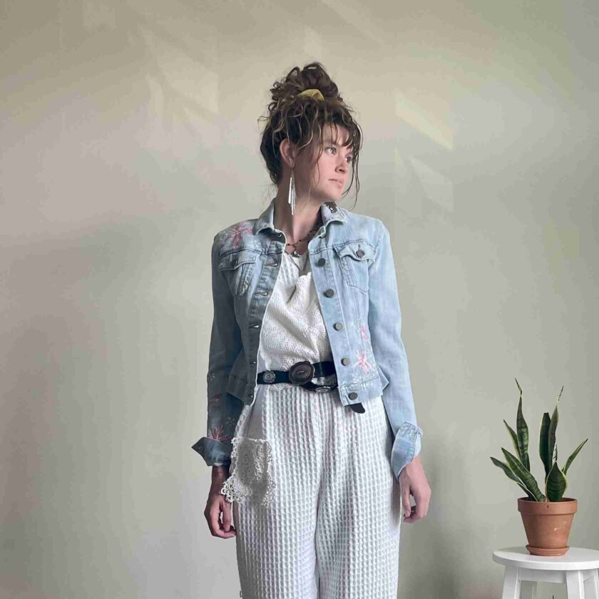 a woman in white pants and a jean jacket.