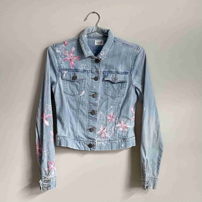 a denim jacket with pink flowers on it.
