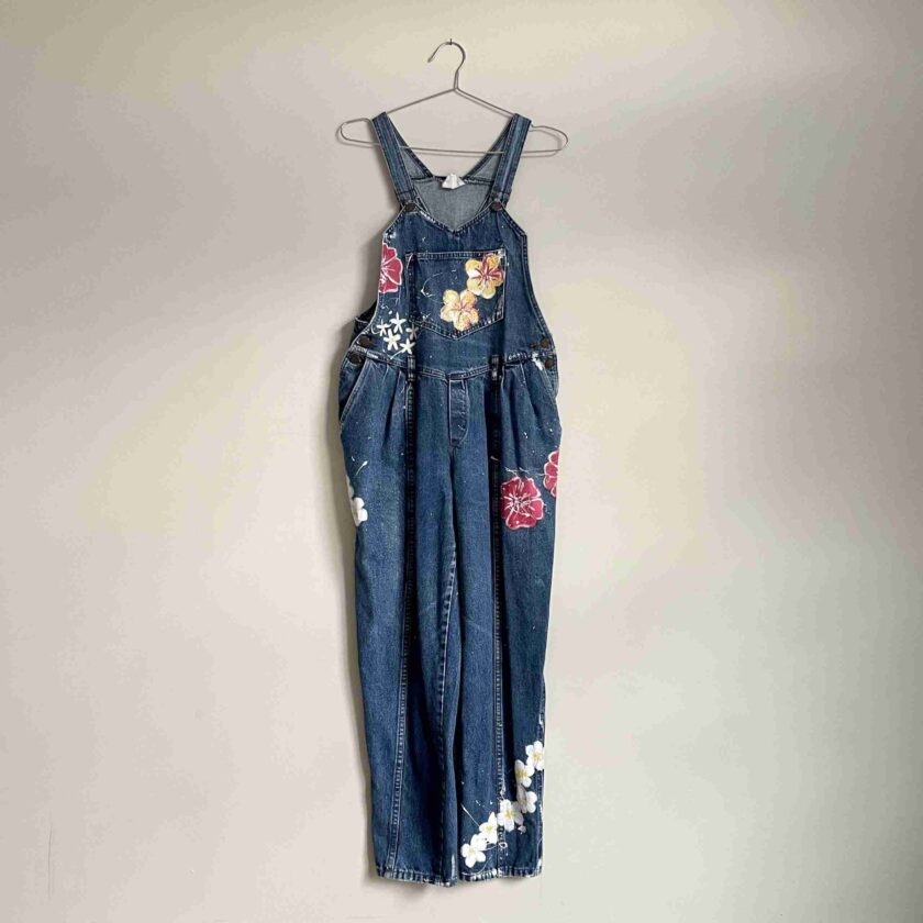 a denim dress with flowers on it hanging on a wall.