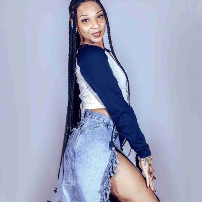 a woman with long braids and a denim skirt.