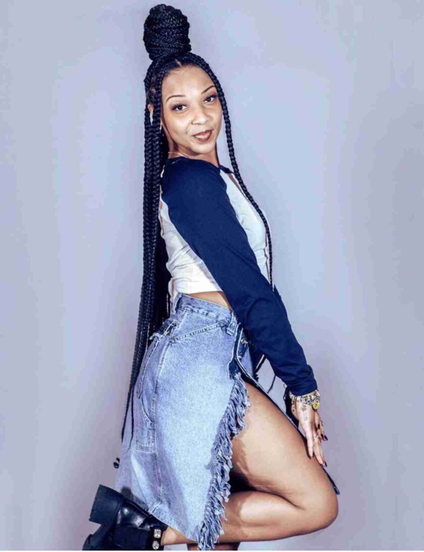 a woman with long braids and a denim skirt.