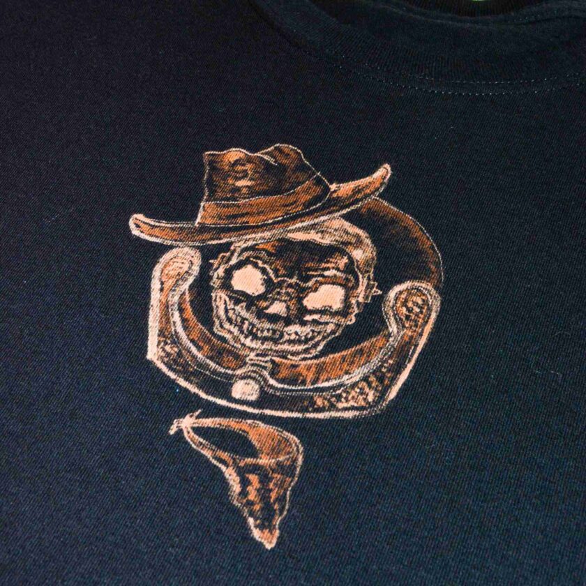 a t - shirt with a drawing of a skull wearing a cowboy hat.
