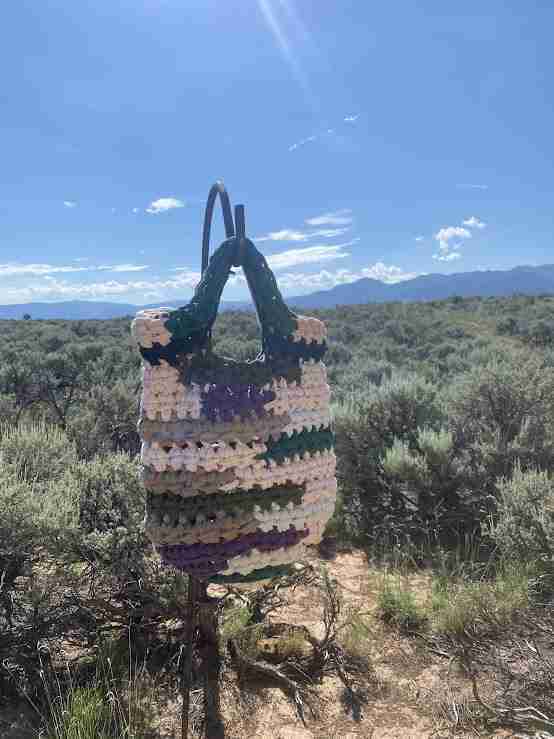 a crocheted bag sitting on top of a metal pole.