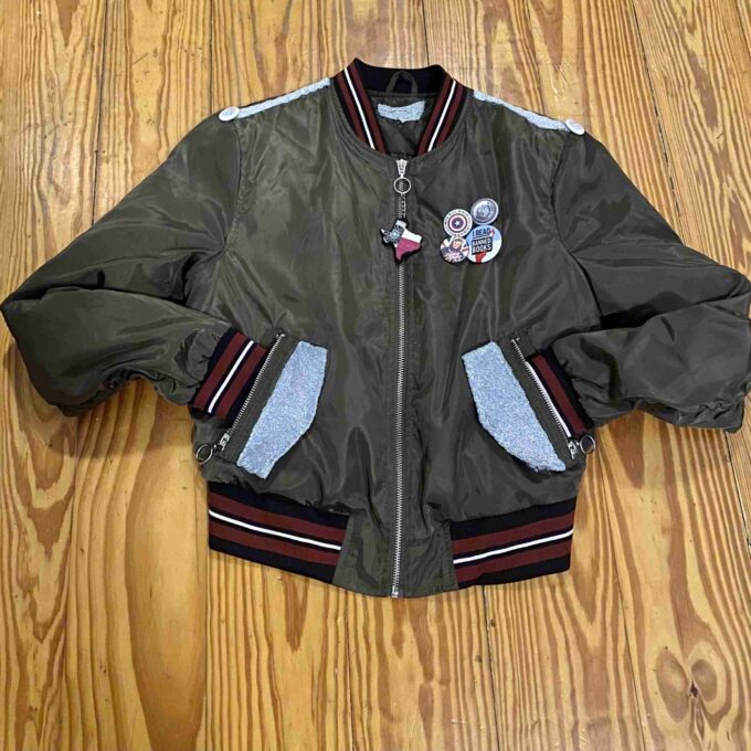a green bomber jacket with patches on the sleeves.