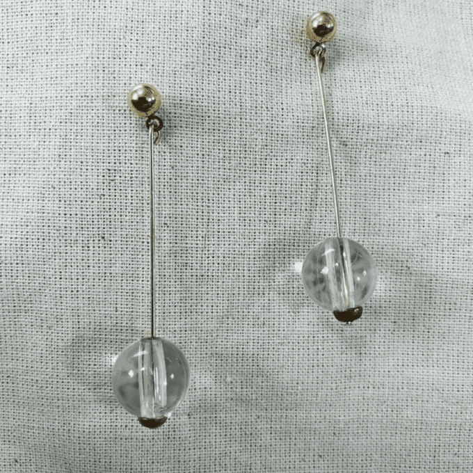 a pair of earrings on a white cloth.
