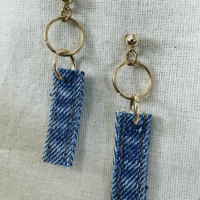 a pair of blue and white earrings on a white cloth.