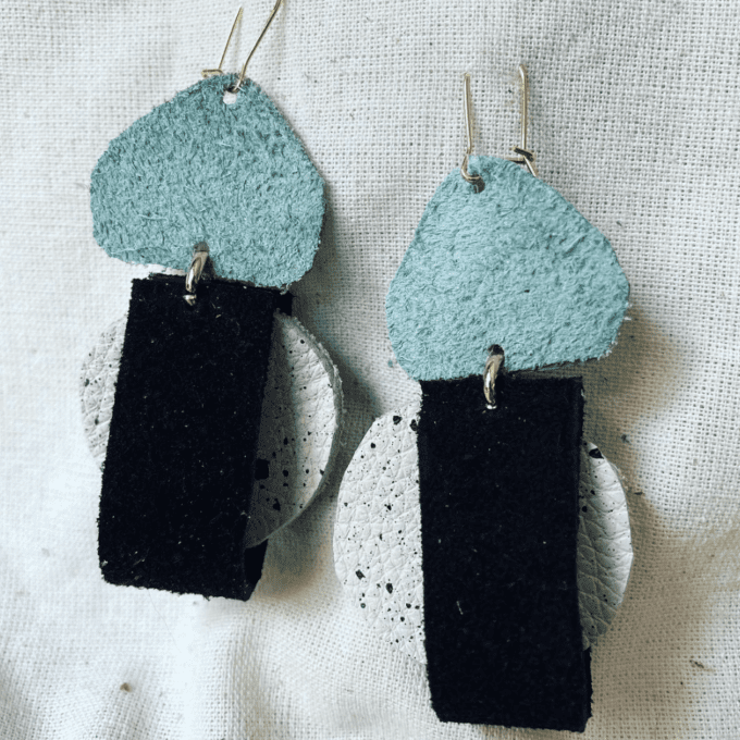 a pair of black and blue earrings on a white surface.