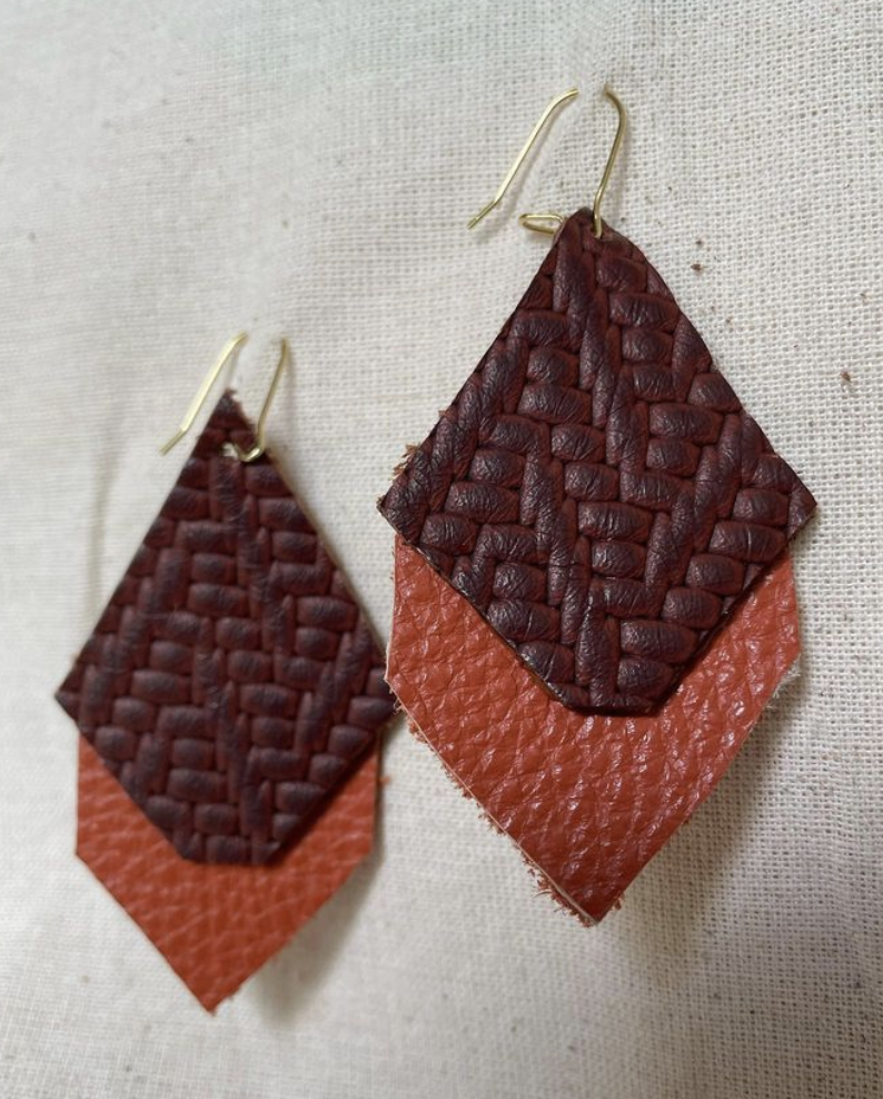 a pair of brown and orange leather earrings.