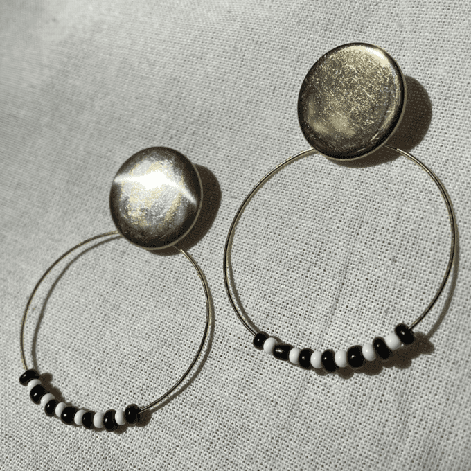 a pair of black and white beaded hoop earrings.