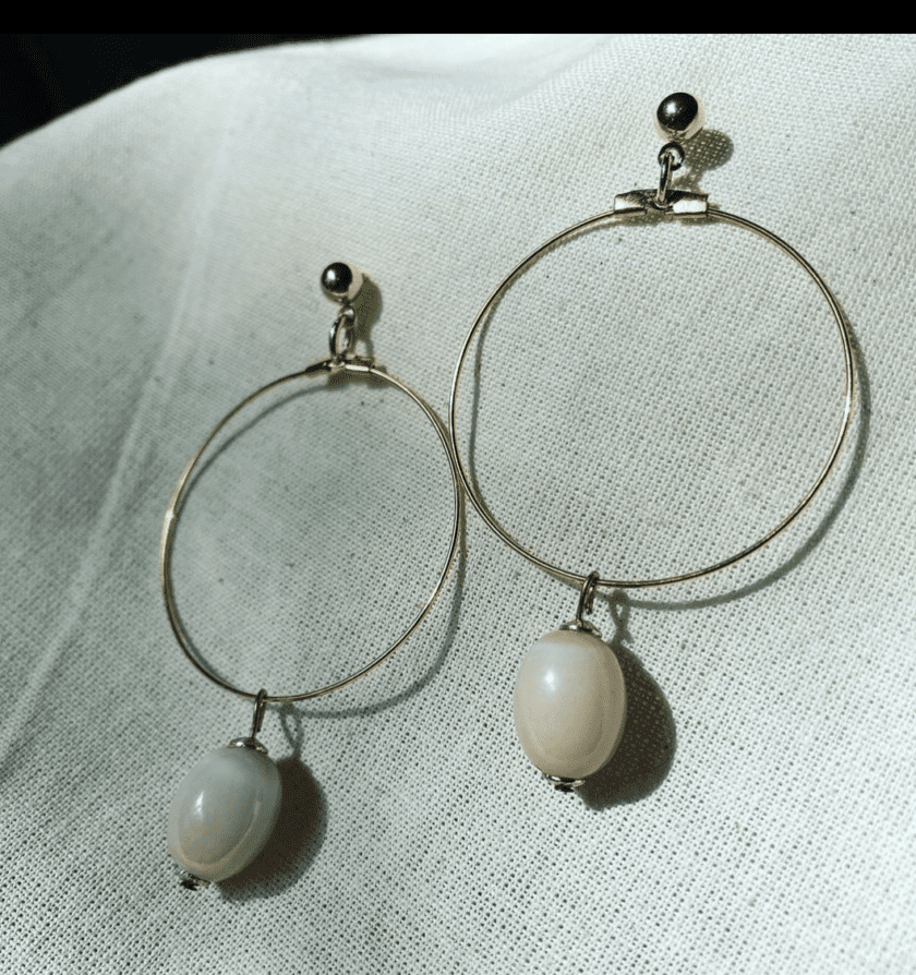 a pair of gold hoop earrings with pink beads.