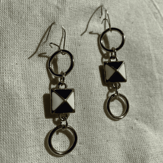 a pair of earrings sitting on top of a white cloth.