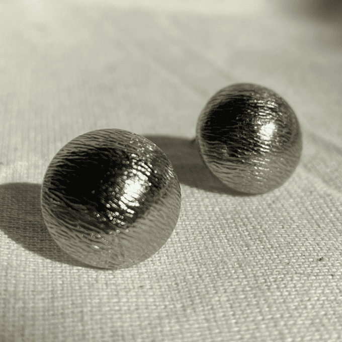 a pair of shiny silver balls sitting on top of a white cloth.