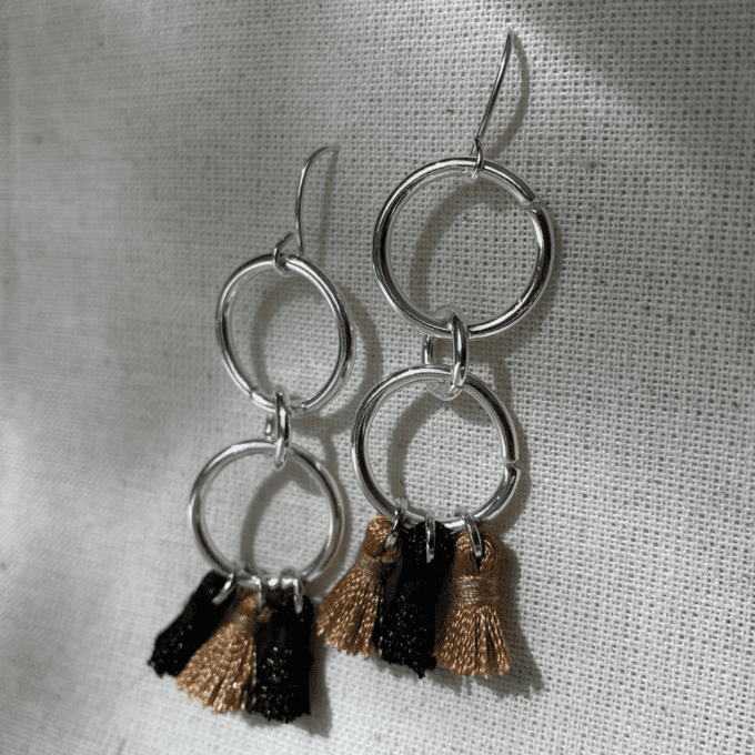 a pair of earrings with tassels hanging from them.