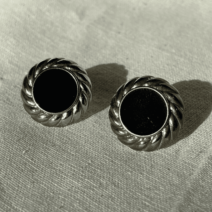 a pair of earrings sitting on top of a white cloth.
