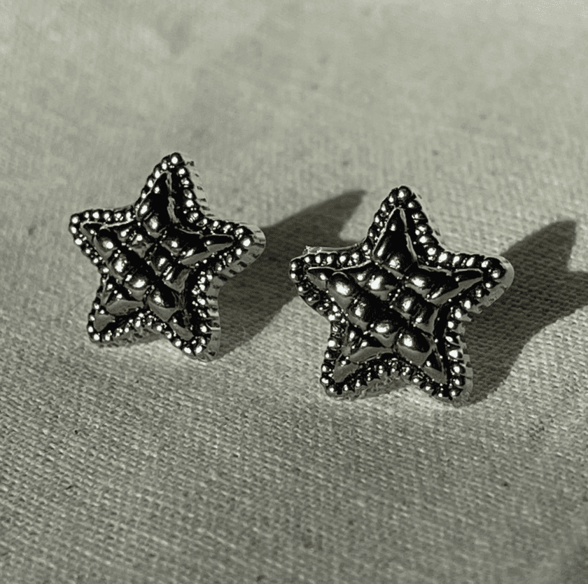 a pair of star shaped earrings sitting on top of a table.