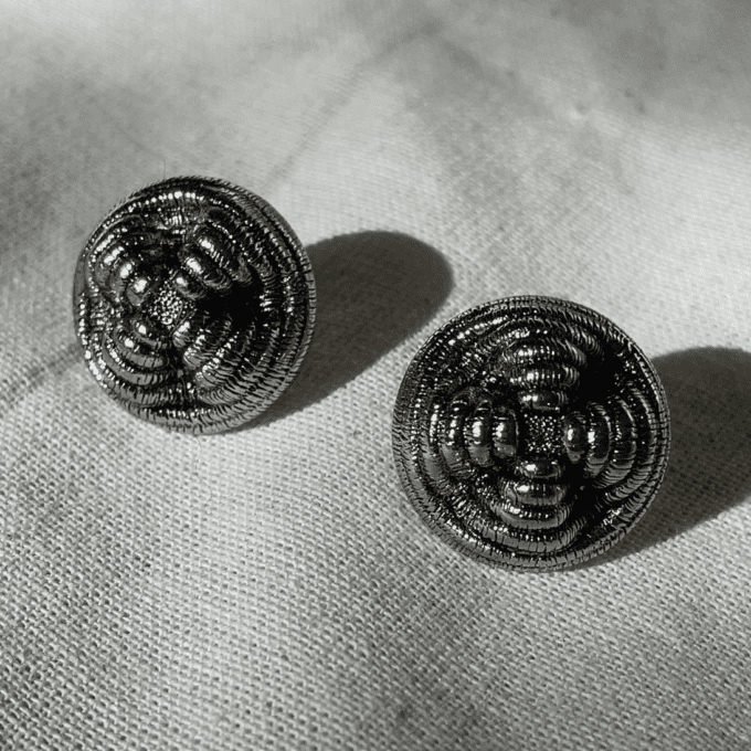 a pair of earrings sitting on top of a white cloth.
