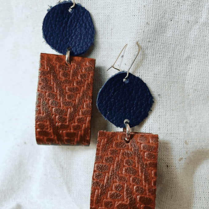 a pair of brown and blue earrings on a white surface.