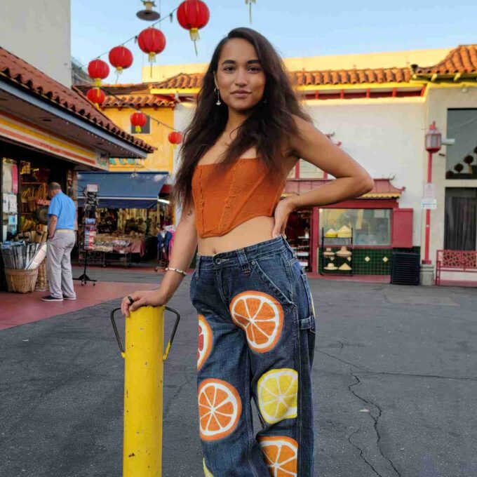 a woman standing next to a pole with oranges on it.