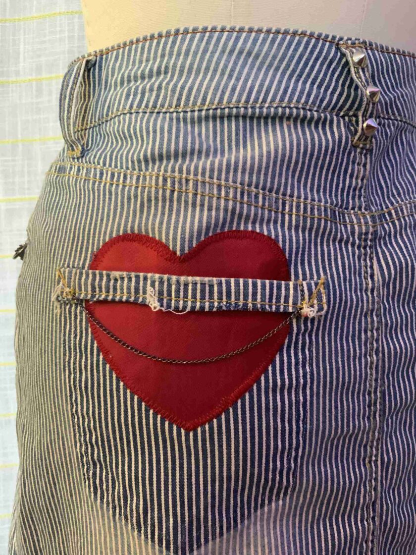 a red heart is in the pocket of a pair of jeans.