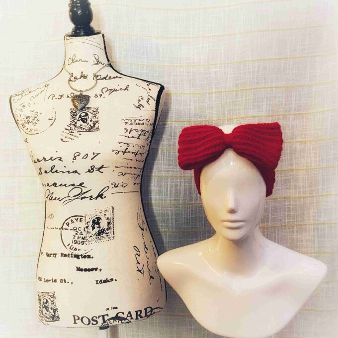 a white mannequin with a red bow on top of it.