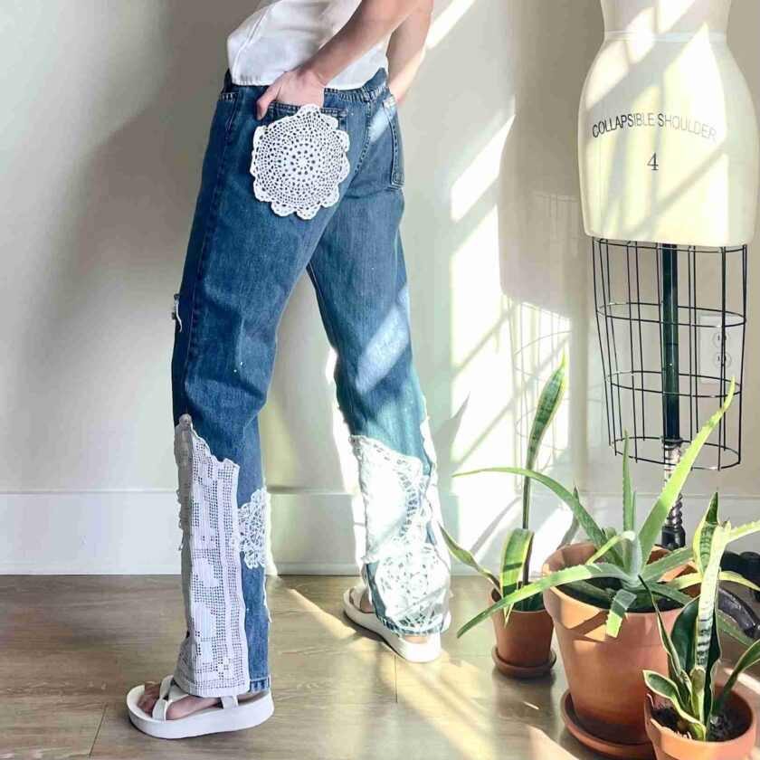 a man in a white shirt and jeans standing next to a plant.