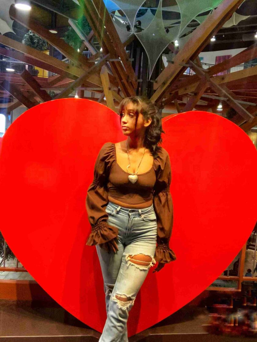 a woman standing in front of a giant heart.