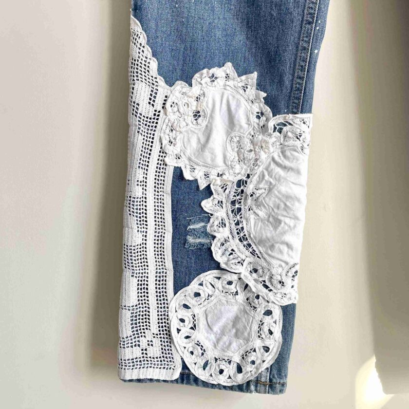 a pair of jeans with lace on them hanging on a wall.