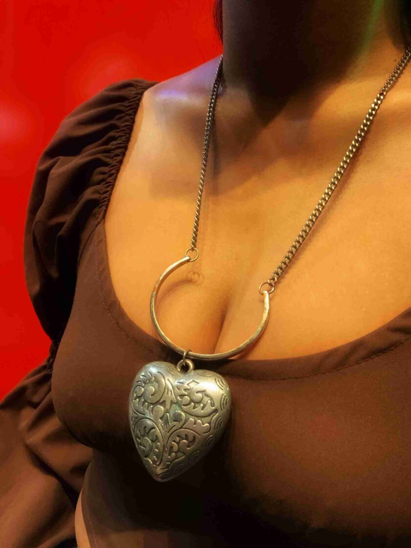 a woman wearing a necklace with a heart shaped pendant.