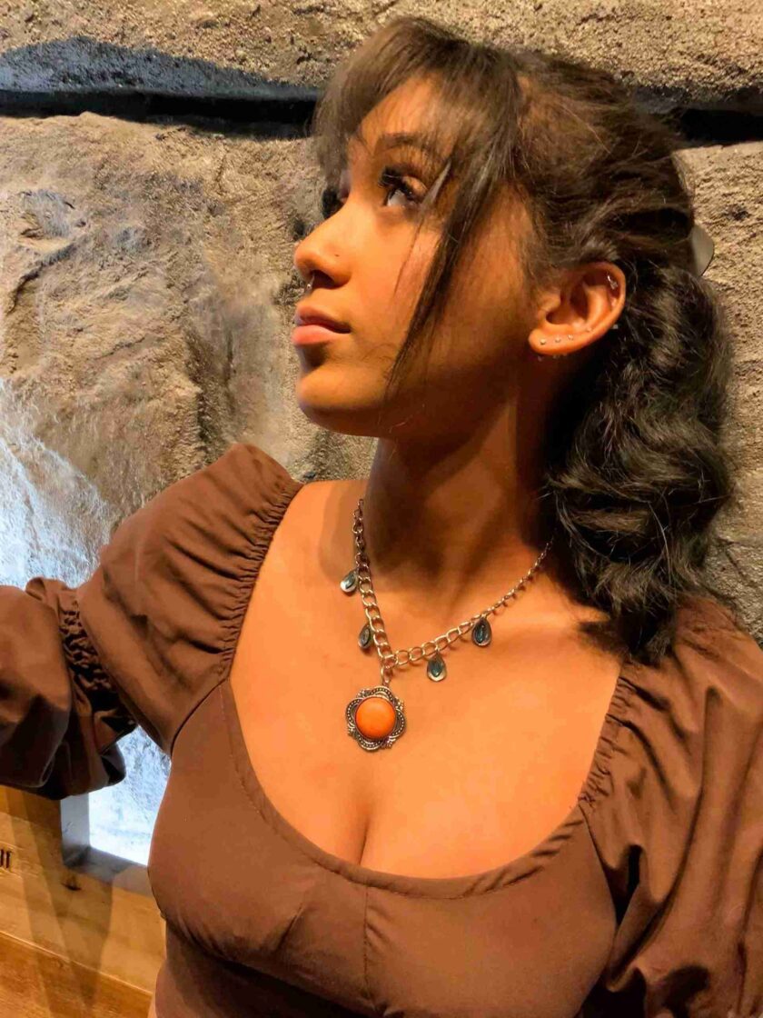 a woman wearing a brown shirt and a necklace.