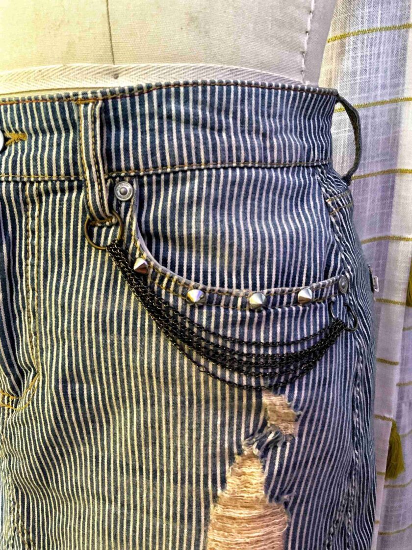 a pair of jeans with holes and chains on them.