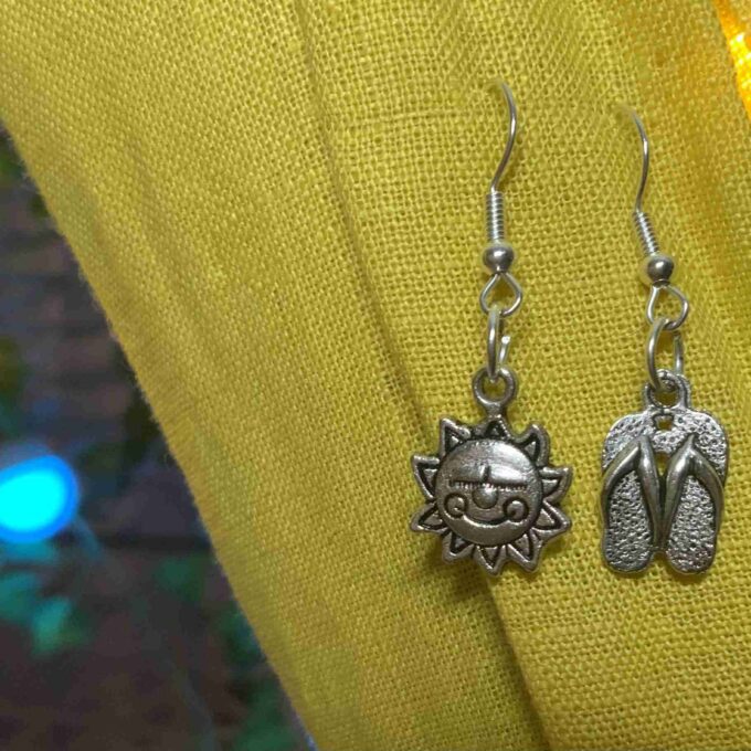 a pair of silver sandals hanging from a pair of earrings.