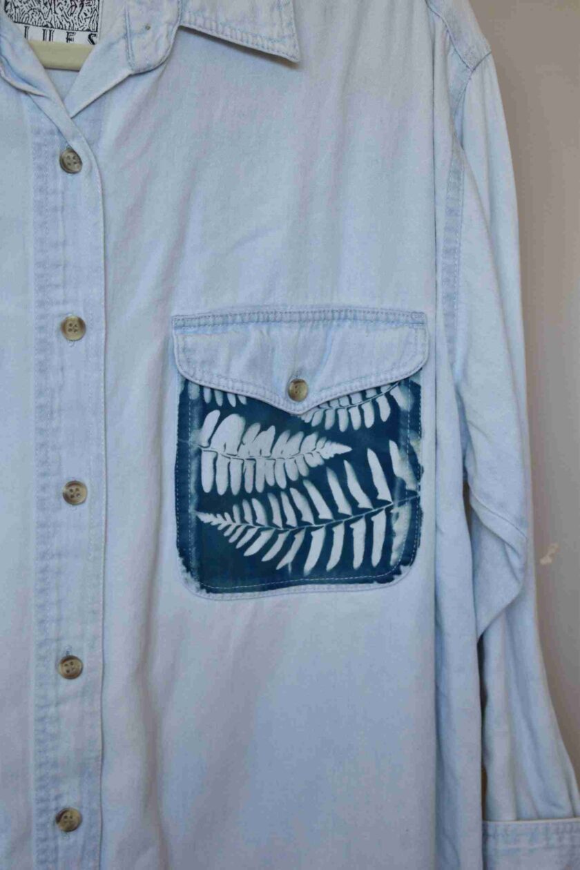 a blue shirt with a white fern on it.