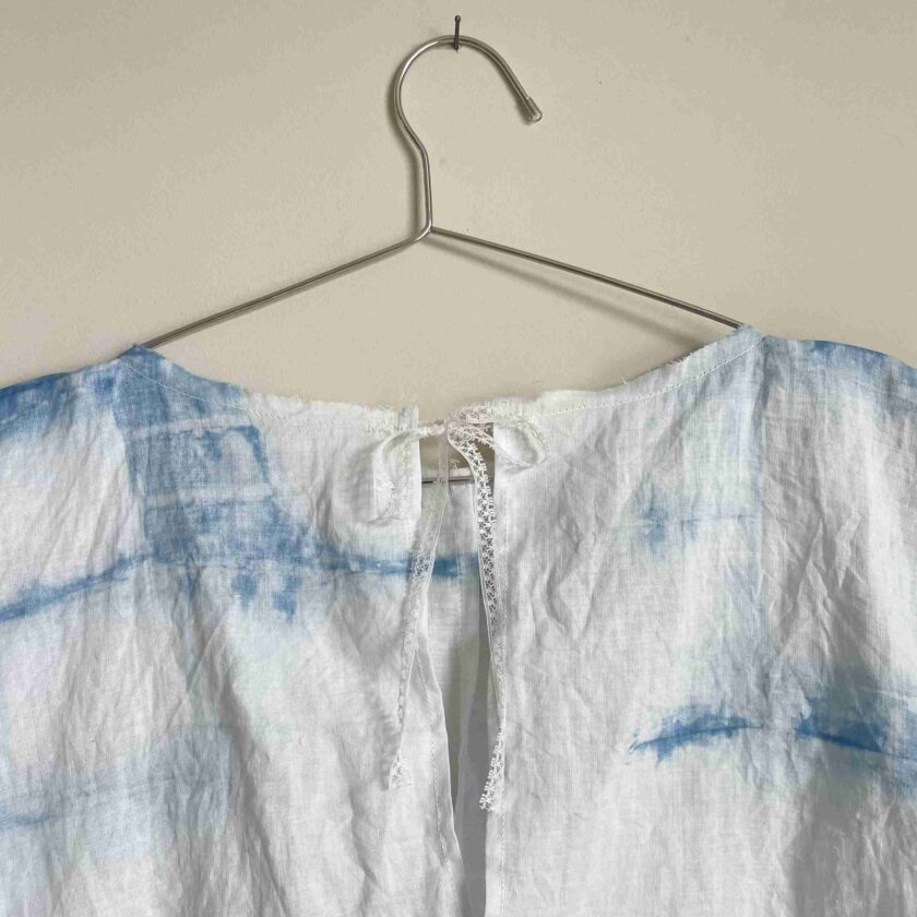 a white and blue tie dye shirt hanging on a hanger.