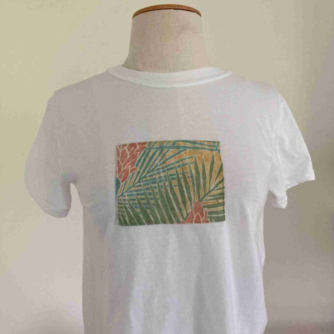 a white t - shirt with palm leaves on it.