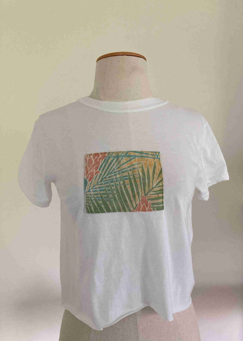 a white t - shirt with palm leaves on it.