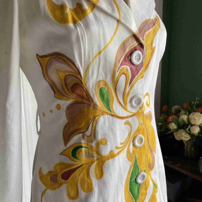 a white dress with yellow and green designs on it.