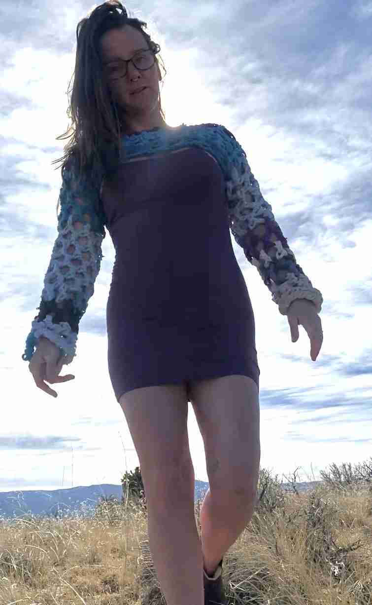 a woman in a short dress standing on a hill.