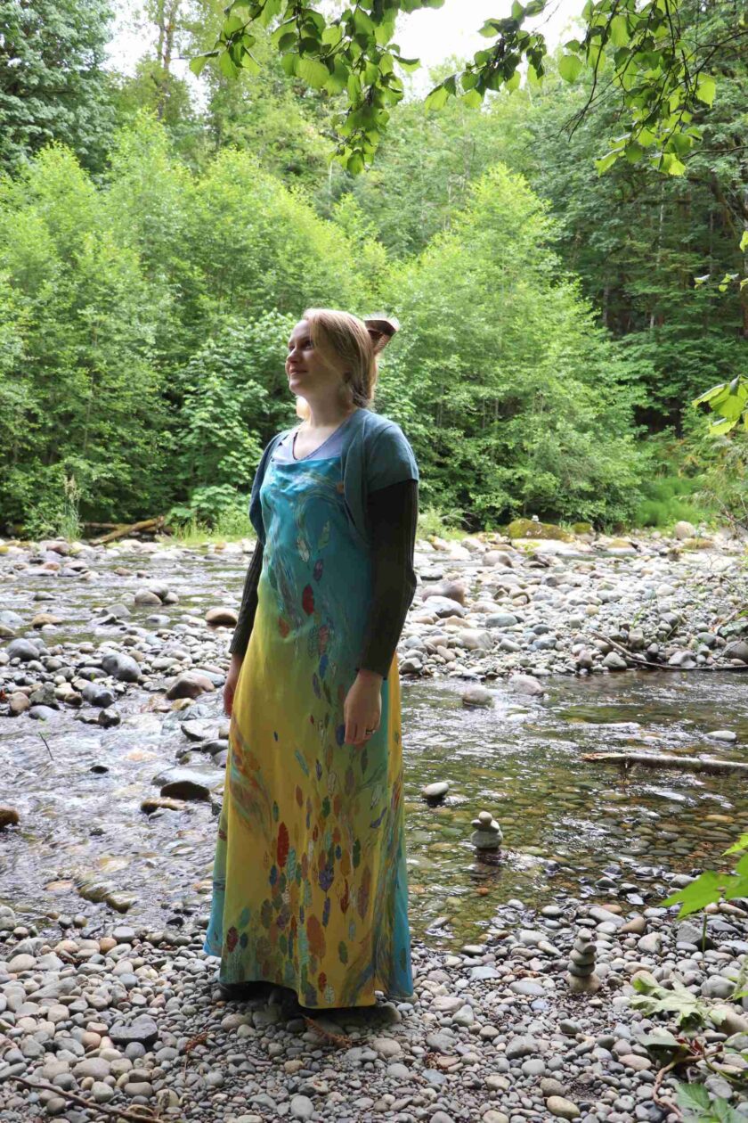 a woman in a dress standing in a stream.