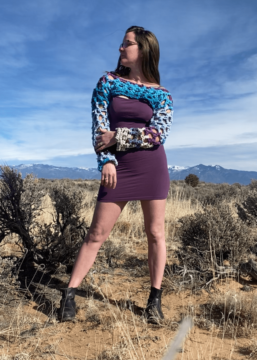 a woman in a purple dress standing in a field.
