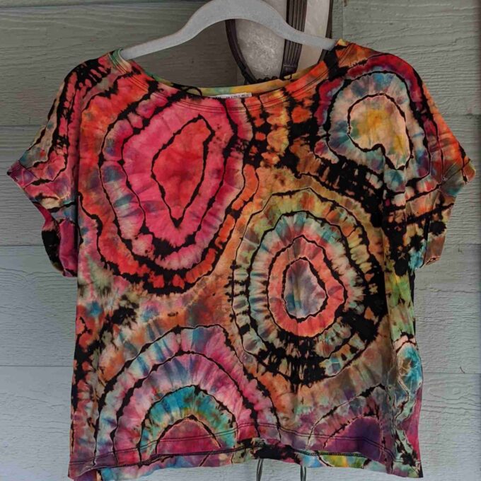 a tie dyed shirt hanging on a wall.