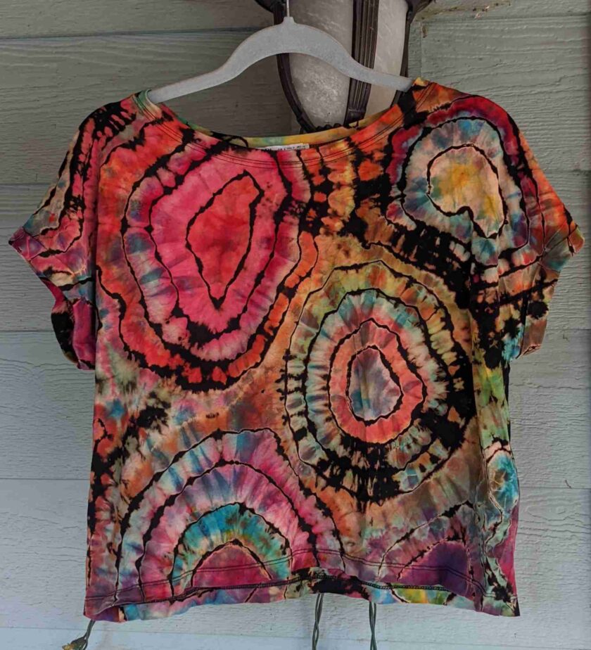 a tie dyed shirt hanging on a wall.