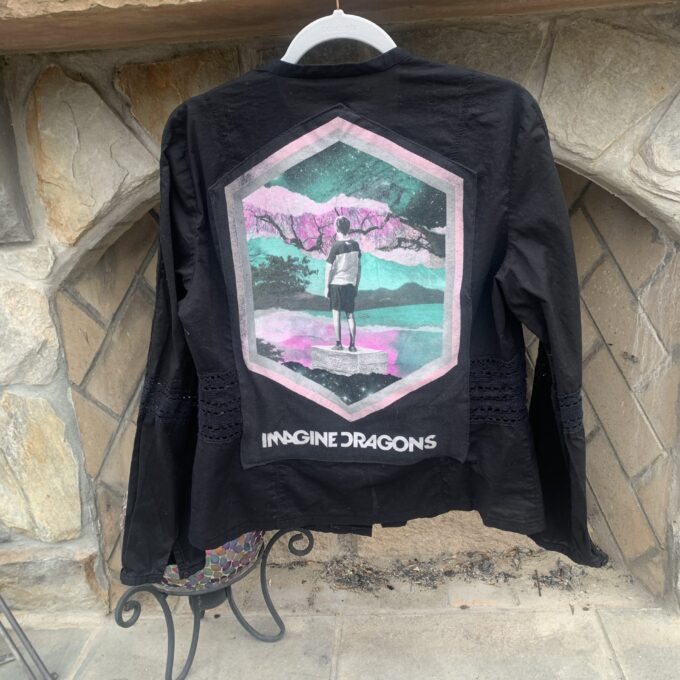 a black jacket with a picture of a person standing in front of a stone fireplace.